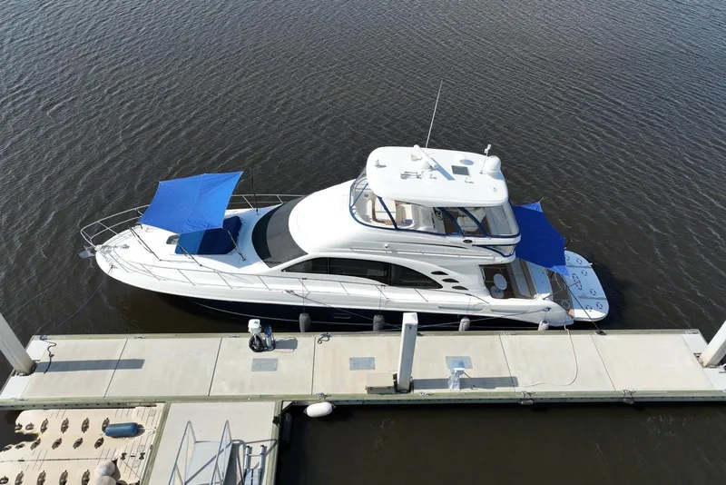 Slide: The Image of 2006 Sea Ray 580 Sedan Bridge yacht docked, featuring blue sunshades and sleek design. - 12