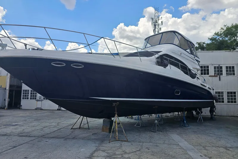 Slide: The Image of 2006 Sea Ray 580 Sedan Bridge yacht on dry dock, blue hull, clear sky background. - 14