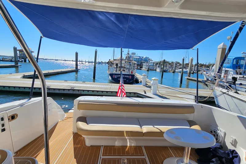 Slide: The Image of 2006 Sea Ray 580 Sedan Bridge yacht docked, featuring a shaded seating area and marina view. - 21