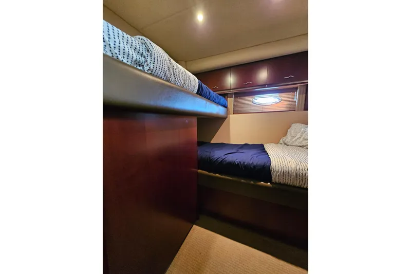 Slide: The Image of Interior of 2006 Sea Ray 580 Sedan Bridge with cozy bunk beds and wooden accents. - 22