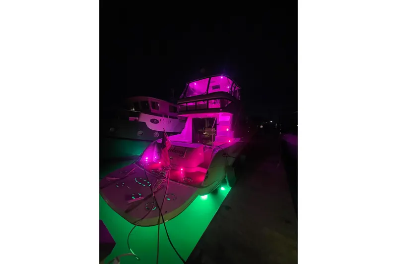 Slide: The Image of 2006 Sea Ray 580 Sedan Bridge yacht illuminated with vibrant pink and green lights at night. - 33