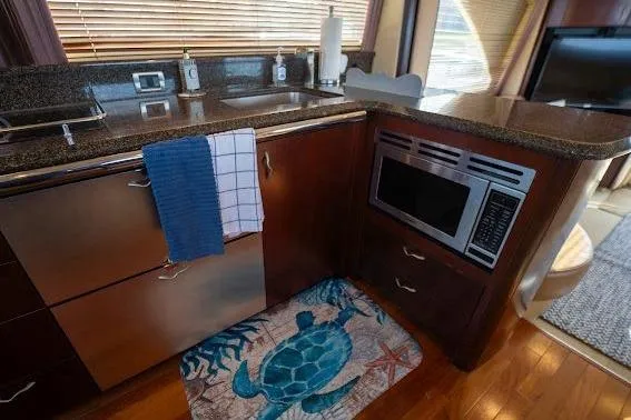 Slide: The Image of 2006 Sea Ray 580 Sedan Bridge kitchen with microwave, sink, and turtle-themed rug. - 43