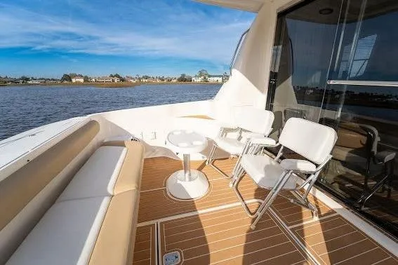 Slide: The Image of 2006 Sea Ray 580 Sedan Bridge yacht deck with seating, overlooking serene water. - 50