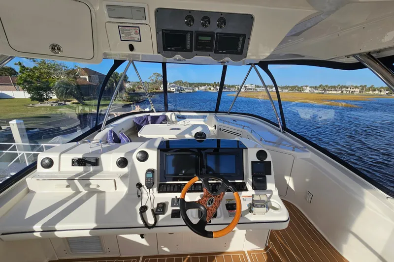 Slide: The Image of 2006 Sea Ray 580 Sedan Bridge helm with modern controls and scenic waterway view. - 53