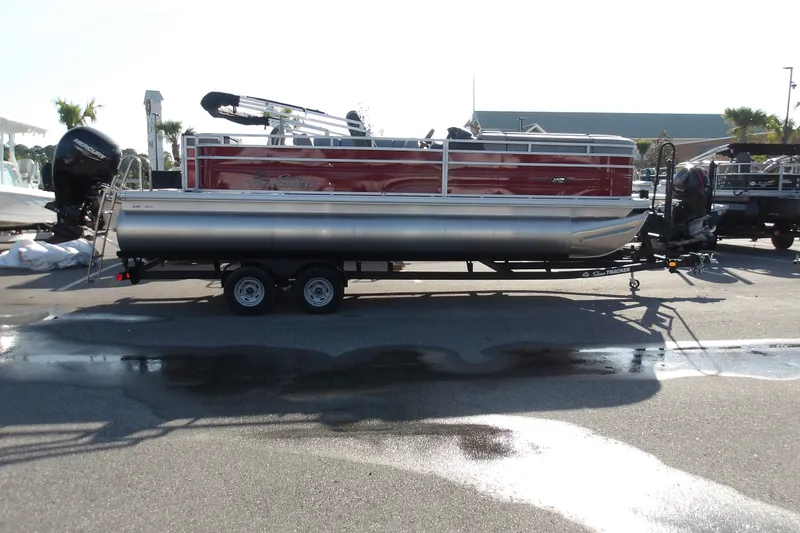 The Image of 2026 Sun Tracker SportFish 22 DLX pontoon boat on trailer, parked outdoors. - 1