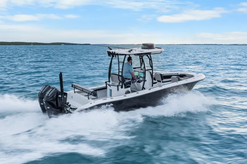 Slide: The Image of 2025 Yellowfin 26 Hybrid boat cruising on open water under a clear blue sky. - 12