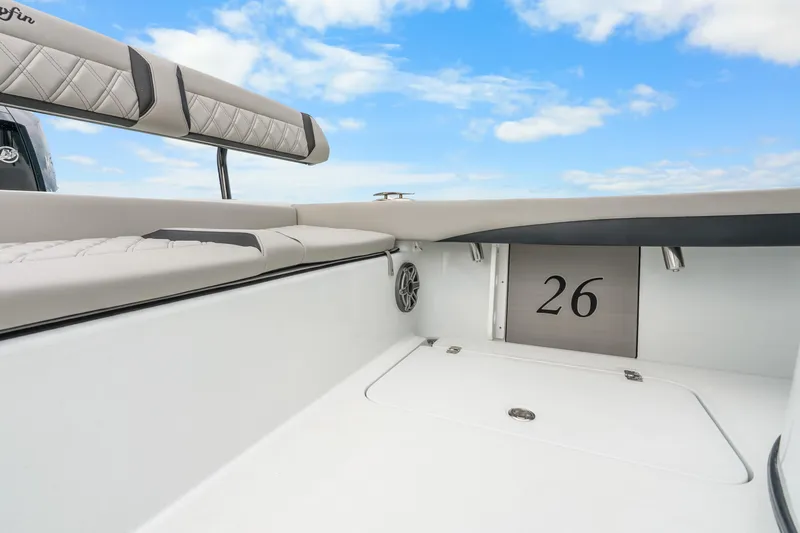 Slide: The Image of 2025 Yellowfin 26 Hybrid boat interior with cushioned seating and storage, under a clear blue sky. - 34