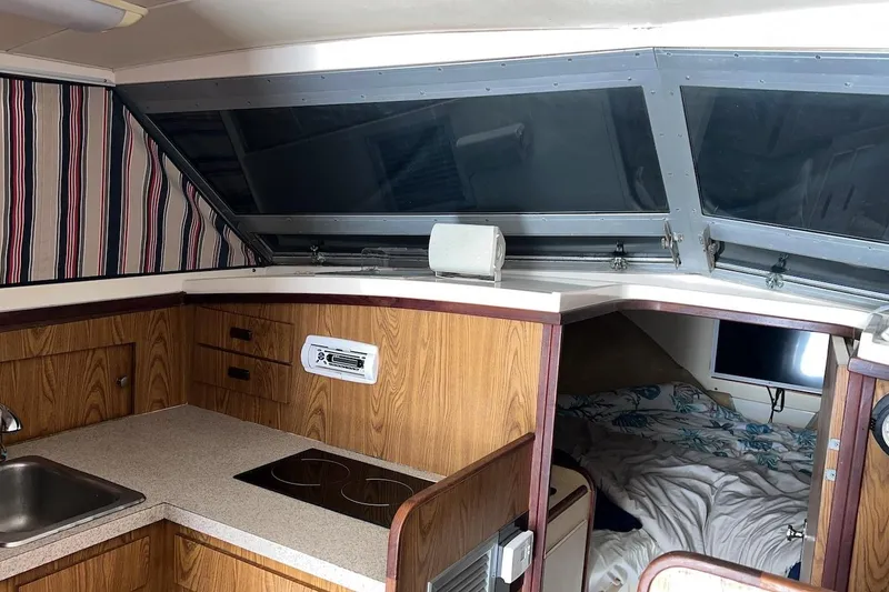 Slide: The Image of 1981 Bertram 33 Sport Fisherman interior kitchen with wood cabinets and striped curtains. - 11
