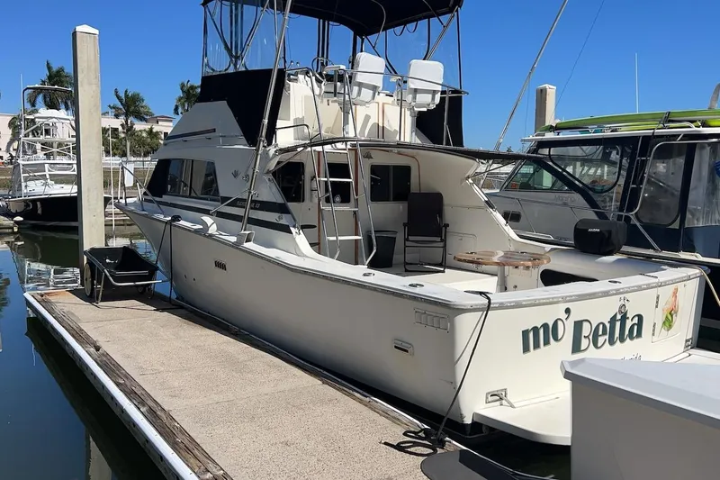 Slide: The Image of 1981 Bertram 33 Sport Fisherman docked at marina with modern buildings in background. - 4