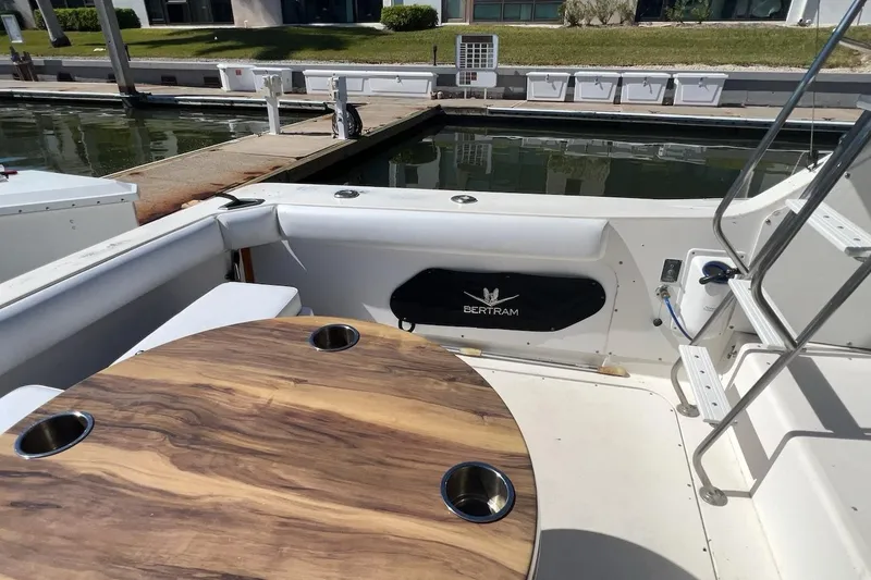 Slide: The Image of 1981 Bertram 33 Sport Fisherman boat interior with seating and table in marina. - 7