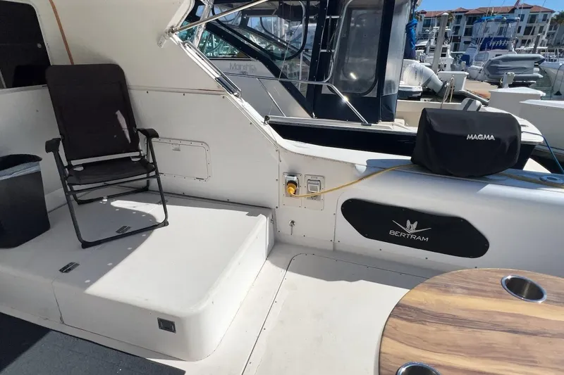 Slide: The Image of 1981 Bertram 33 Sport Fisherman boat interior with wooden table and marina view. - 8