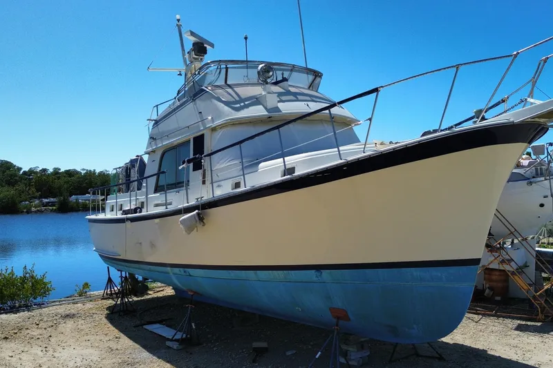 Slide: The Image of 1976 Hatterus 42 Long Range Cruiser docked by a serene lake under clear blue skies. - 2