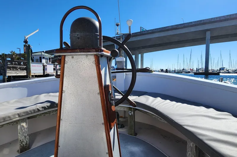 Slide: The Image of 1996 Tillotson-Pearson Motorsailer 32 helm with marina view under clear blue sky. - 11