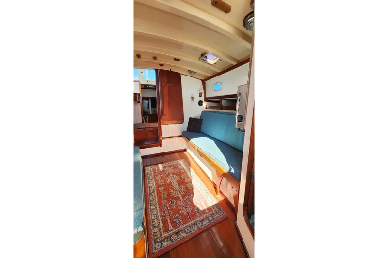 Slide: The Image of Cozy interior of 1996 Tillotson-Pearson Motorsailer 32 with wooden accents and blue seating. - 28