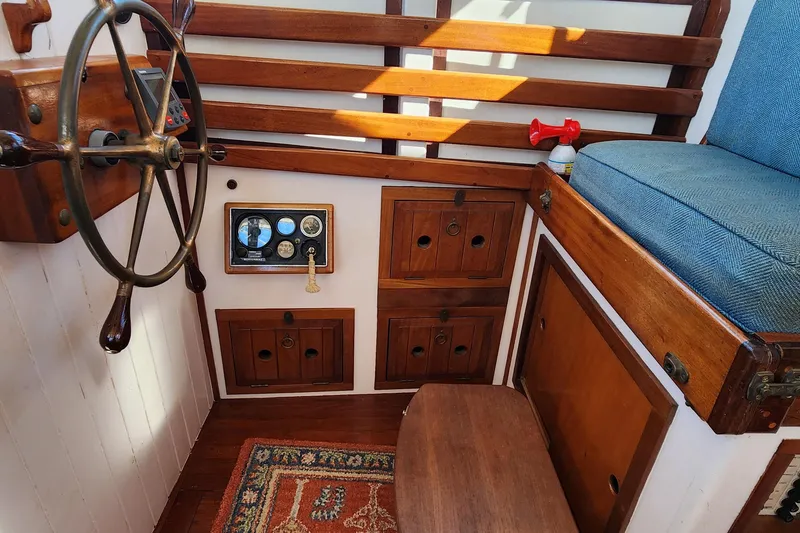 Slide: The Image of 1996 Tillotson-Pearson Motorsailer 32 interior with wooden helm, gauges, and seating. - 45