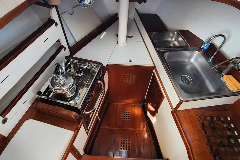 Slide: The Image of Compact kitchen in 1996 Tillotson-Pearson Motorsailer 32, featuring stove, sink, and wooden cabinetry. - 52