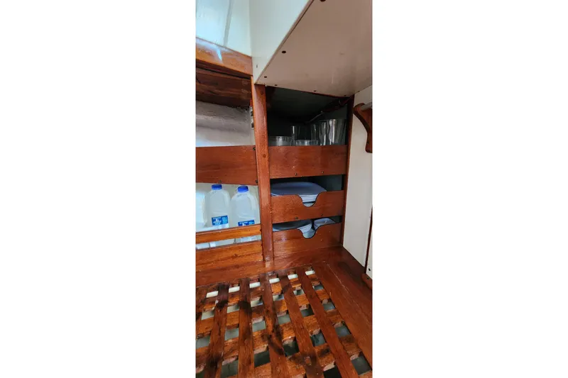 Slide: The Image of Interior storage of 1996 Tillotson-Pearson Motorsailer 32 with wooden shelves and water jugs. - 57