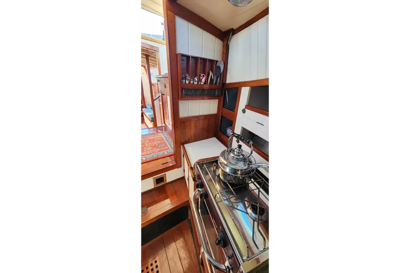 Slide: The Image of Cozy kitchen area in 1996 Tillotson-Pearson Motorsailer 32 with stove and wooden cabinetry. - 58