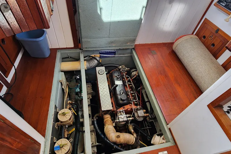 Slide: The Image of Engine room of 1996 Tillotson-Pearson Motorsailer 32 with visible components and wooden flooring. - 61