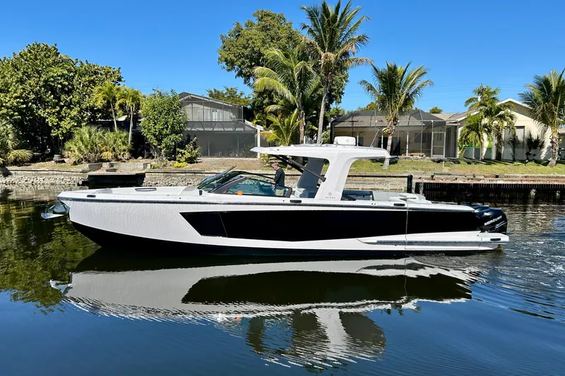 The Image of 2022 Aviara AV40 OB boat on calm water, surrounded by lush greenery and modern homes. - 0