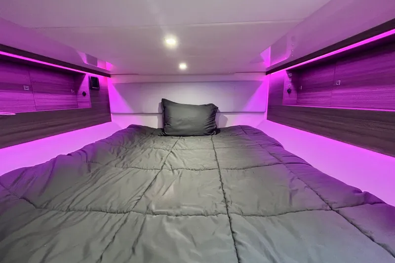 Slide: The Image of 2022 Aviara AV40 OB cabin with cozy bed and ambient purple lighting. - 55