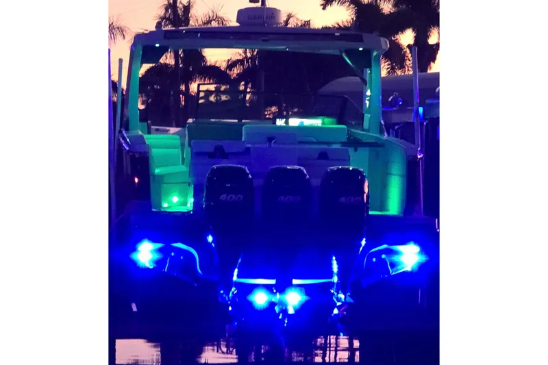 Slide: The Image of 2022 Aviara AV40 OB boat illuminated with vibrant blue and green lights at sunset. - 71