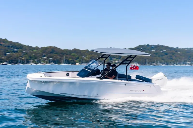 The Image of 2026 Axopar 22 T-Top boat cruising on a scenic lake with hills in the background. - 1