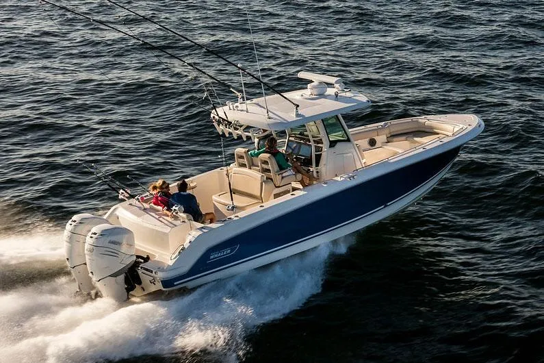 Slide: The Image of Manufacturer Provided Image: 2025 Boston Whaler 330 Outrage cruising on open water, featuring dual engines and fishing rods. - 5