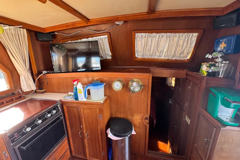 Slide: The Image of 1986 Newburyport 37 yacht interior with wood paneling, kitchen appliances, and a mounted TV. - 22