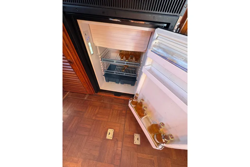 Slide: The Image of Open fridge on Newburyport 37 boat, stocked with bottled drinks, wooden floor visible. - 26
