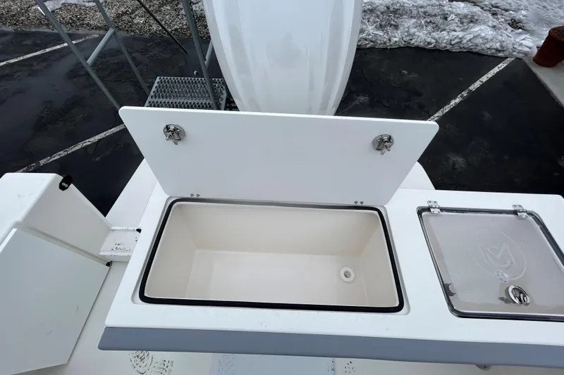 Slide: The Image of 2026 May-Craft 245 Offshore CC boat storage compartment with open lid, showcasing interior space. - 22