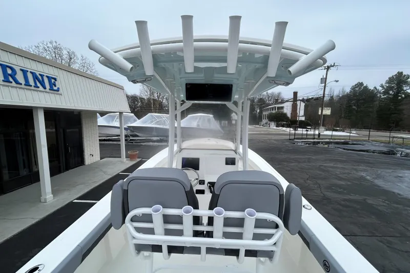 Slide: The Image of 2026 May-Craft 245 Offshore CC boat with T-top and rod holders, parked near a marine store. - 26