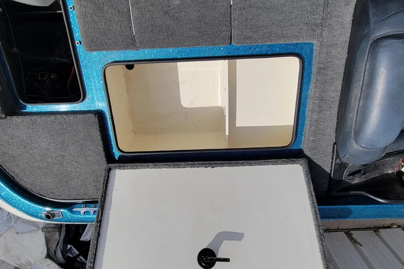 Slide: The Image of 2000 Ranger 522DVX Comanche boat interior storage compartment with blue trim and gray carpet. - 25