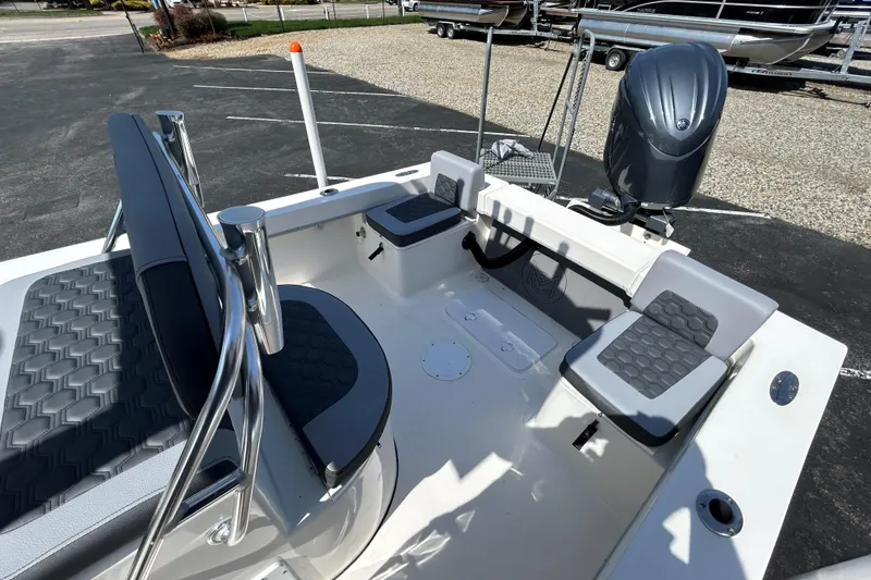 Slide: The Image of 2026 May-Craft 238 Offshore CC boat interior with seating and motor, parked on asphalt. - 14