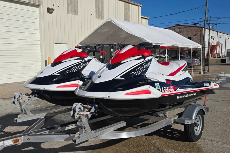 Slide: The Image of 2021 Yamaha WaveRunner VX Deluxe jet skis on a trailer, parked outdoors. - 2
