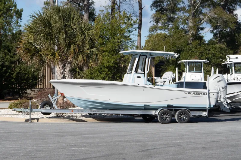 The Image of 2026 Blazer Bay Makaira 2600 boat on trailer, parked outdoors with trees in background. - 1