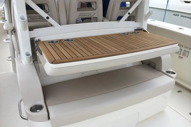 Slide: The Image of Manufacturer Provided Image: 2025 Boston Whaler 380 Outrage boat seating with wooden table and cup holders. - 14