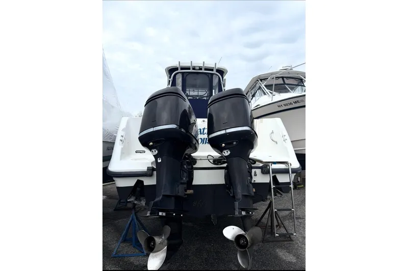Slide: The Image of 2005 Boston Whaler 255 Conquest boat with dual outboard motors, docked on land. - 29
