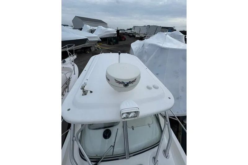 Slide: The Image of 2005 Boston Whaler 255 Conquest boat with radar, docked among covered vessels. - 7