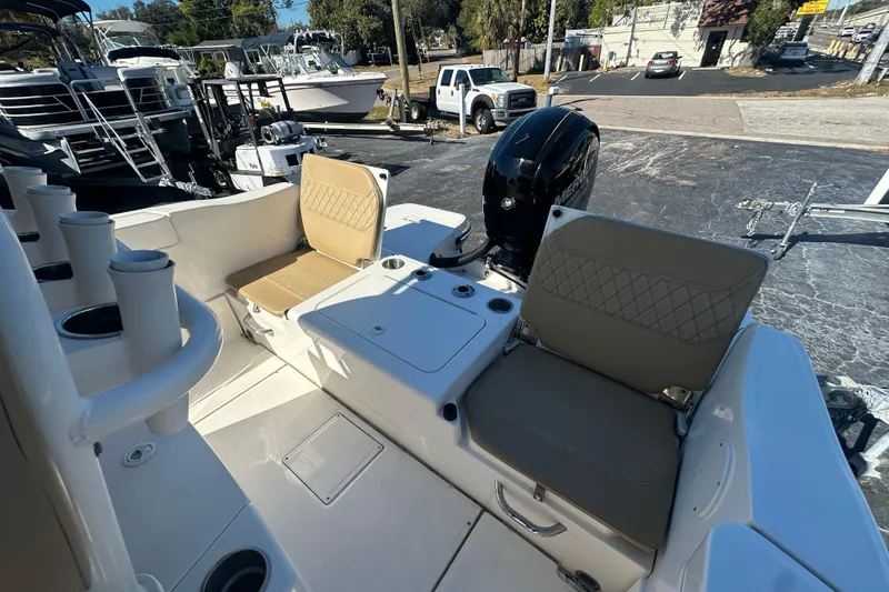 Slide: The Image of 2021 Bayliner Trophy T22CC boat interior with seating and motor, parked outdoors. - 11