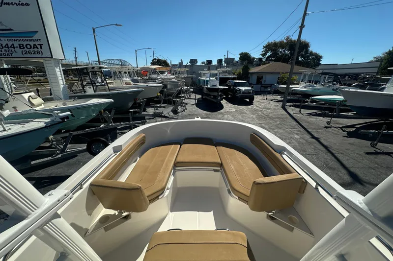 Slide: The Image of 2021 Bayliner Trophy T22CC boat with tan seating, displayed at a dealership. - 20
