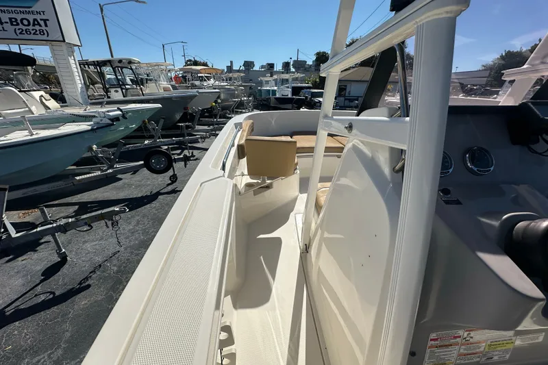 Slide: The Image of 2021 Bayliner Trophy T22CC boat interior, showcasing seating and console, in a marina setting. - 21