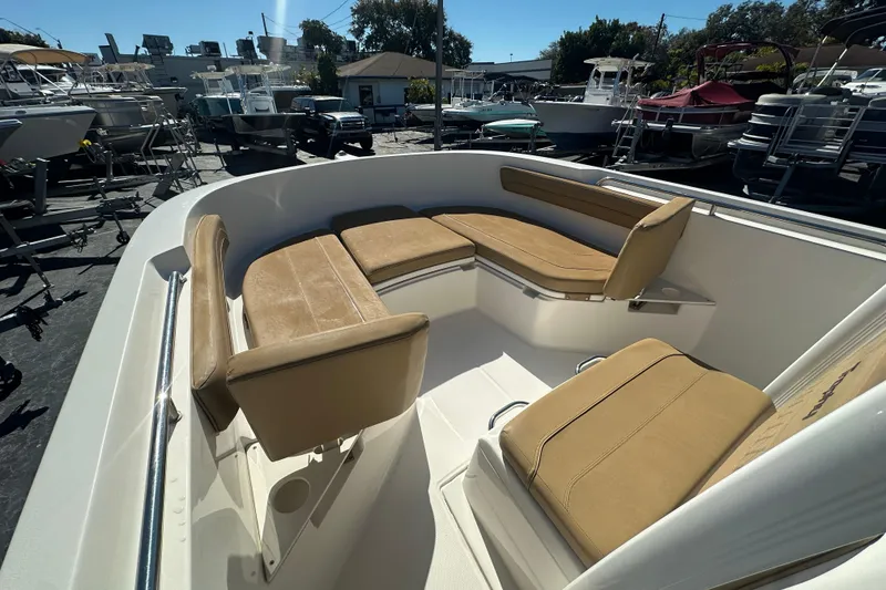 Slide: The Image of 2021 Bayliner Trophy T22CC boat with tan seating, docked among other boats. - 22