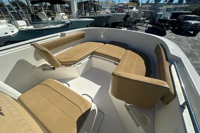 Slide: The Image of 2021 Bayliner Trophy T22CC boat with tan cushioned seating in a marina setting. - 24