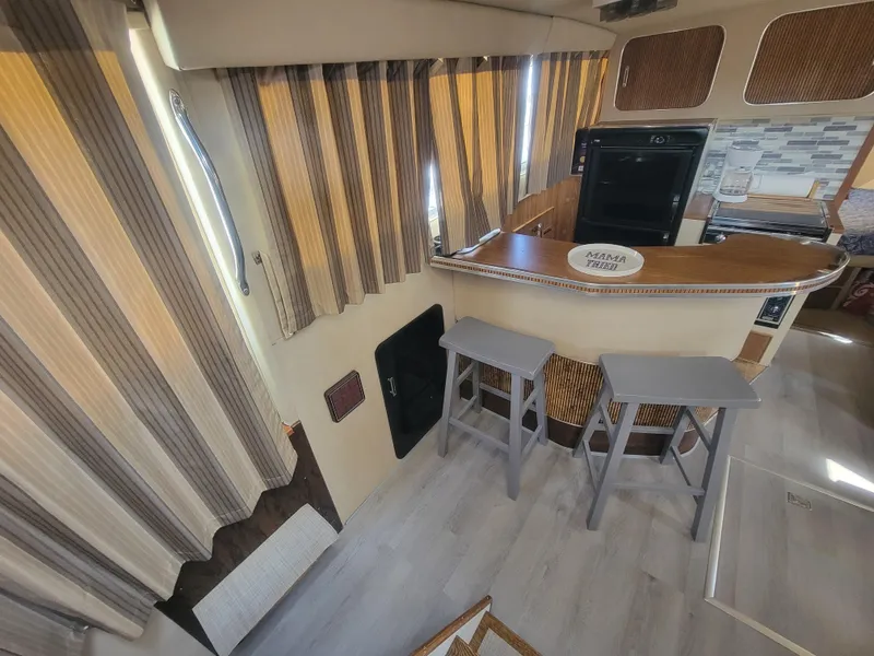 Slide: The Image of 1986 Chris-Craft 381 Catalina interior with bar stools, striped curtains, and modern flooring. - 15