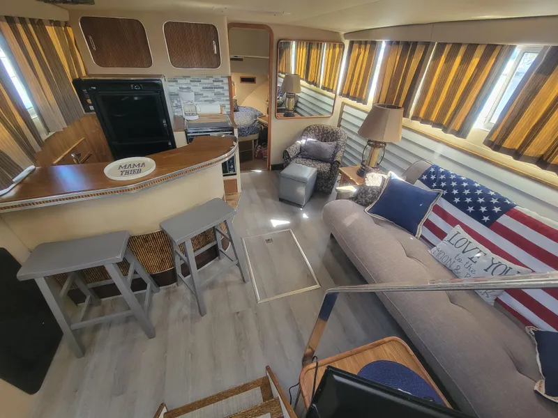 Slide: The Image of 1986 Chris-Craft 381 Catalina interior with cozy seating, bar area, and American flag decor. - 16