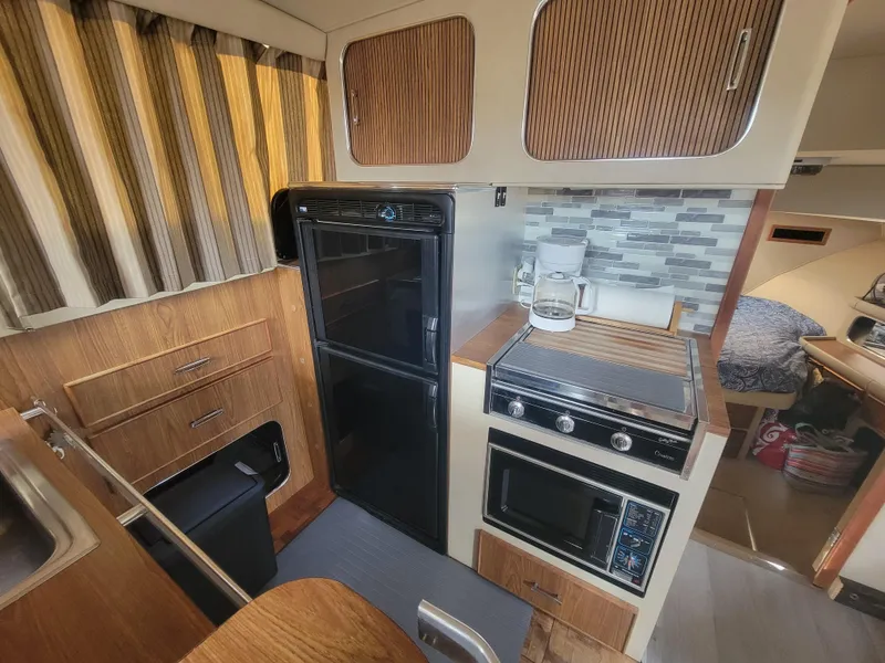 Slide: The Image of 1986 Chris-Craft 381 Catalina interior kitchen with stove, fridge, and wood cabinetry. - 25