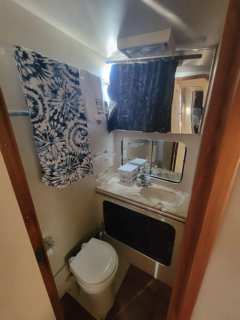 Slide: The Image of 1986 Chris-Craft 381 Catalina bathroom with toilet, sink, and patterned towel. - 29