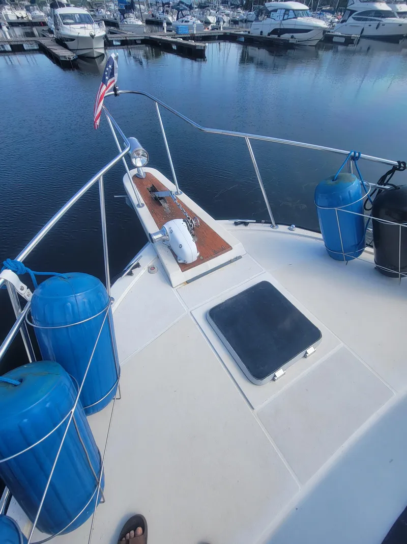 Slide: The Image of 1986 Chris-Craft 381 Catalina yacht docked, featuring deck view with blue fenders and American flag. - 5