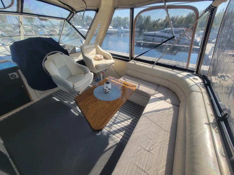 Slide: The Image of 1986 Chris-Craft 381 Catalina interior with seating, table, and marina view. - 9